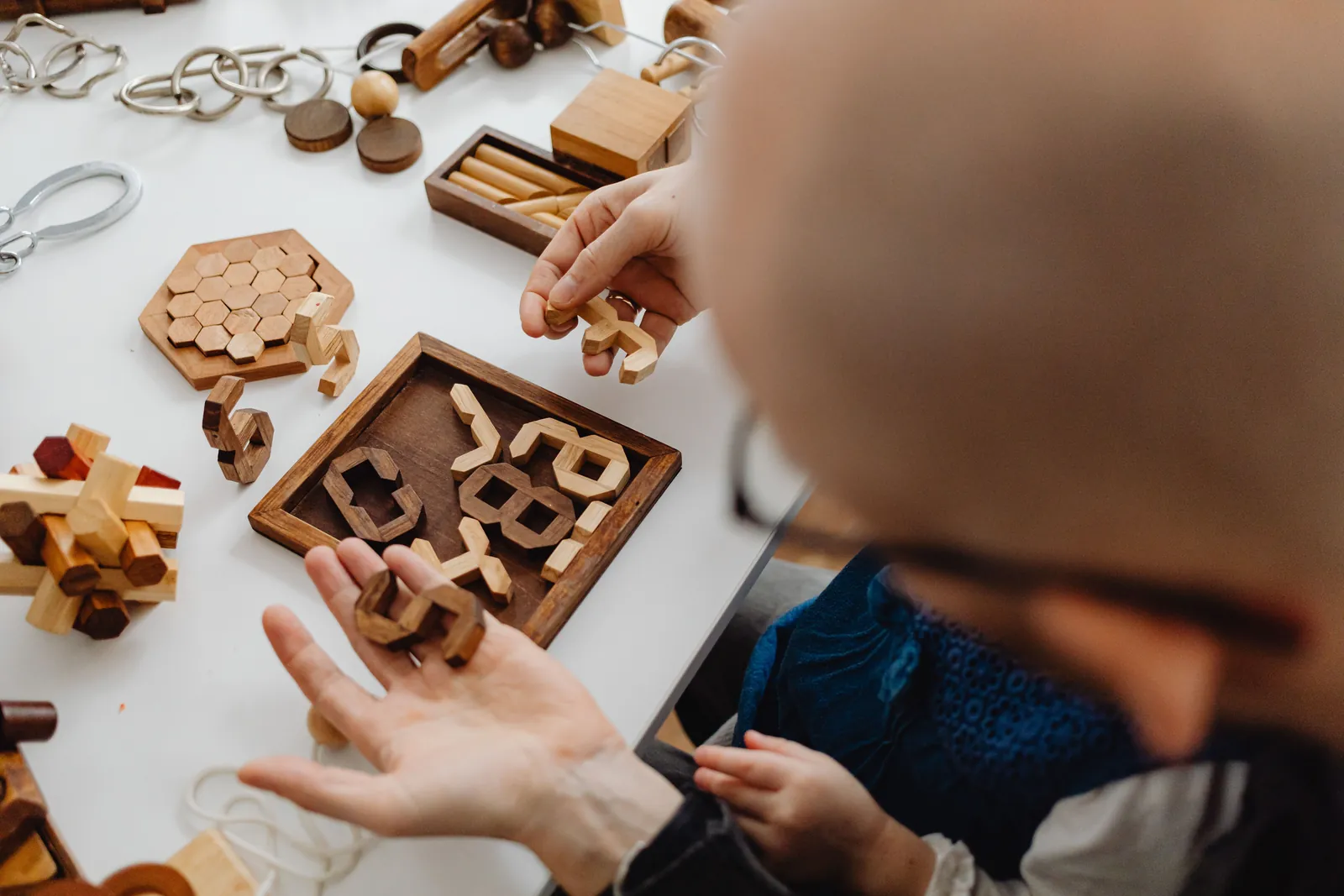 Hands exploring wooden cognitive puzzles and problem-solving toys